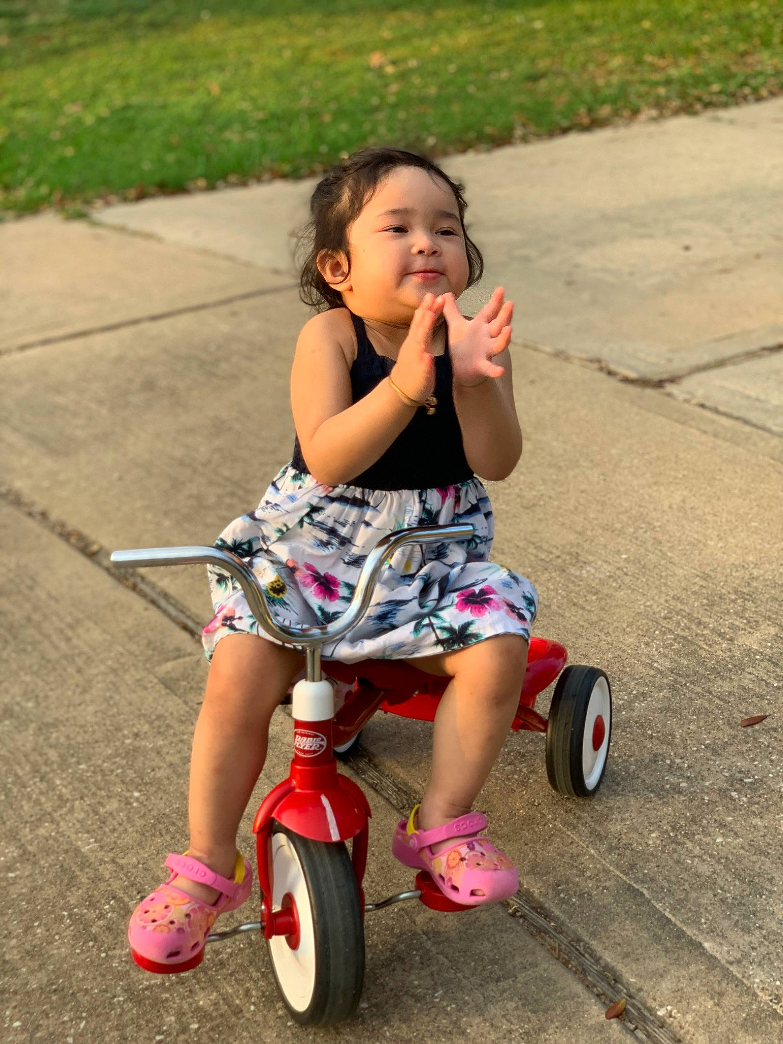 Amelia is registered to the contest to win money with this photo: automotive_tire, baby_toddler_clothing, beauty, bicycle, bicycle_accessory, footwear, fun, grass, happy, mode_of_transport, person, pink, public_space, riding_toy, shoe, smile, summer, tire, toddler, vehicle