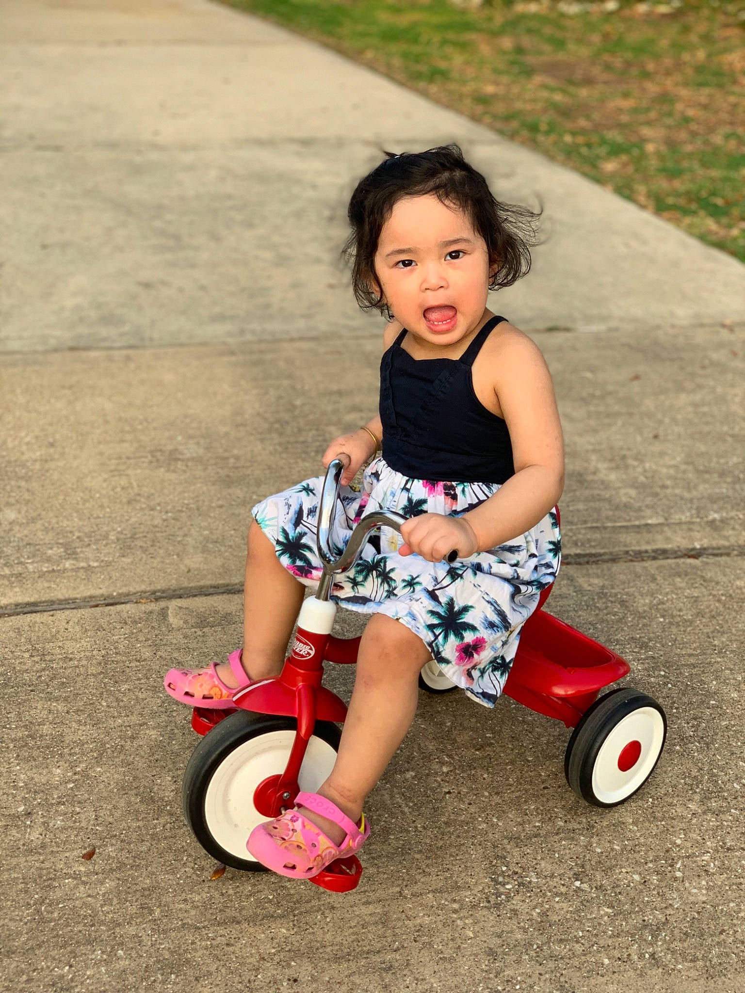 Amelia is registered to the contest to win money with this photo: automotive_tire, baby_toddler_clothing, child, flash_photography, fun, happy, human_leg, leisure, magenta, people_in_nature, person, pink, riding_toy, rolling, shoe, smile, sneakers, tire, toddler, vehicle