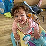 Daisy is registered to the contest to win money with this photo: baby, child, clothing, curly_hair, cute, expression, face, furniture, happy, home, indoor, person, plastic, play, smiling, toddler, toy, walker, wooden_floor, young_child
