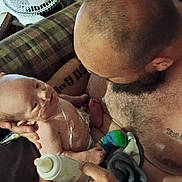 Milo joined the competition — help win amazing prizes! baby, beard, bottle, care, child, couch, family, fan, feeding, hand, indoor, infant, love, man, nasal_tube, parent, plaid, shirtless, skin, tattoo