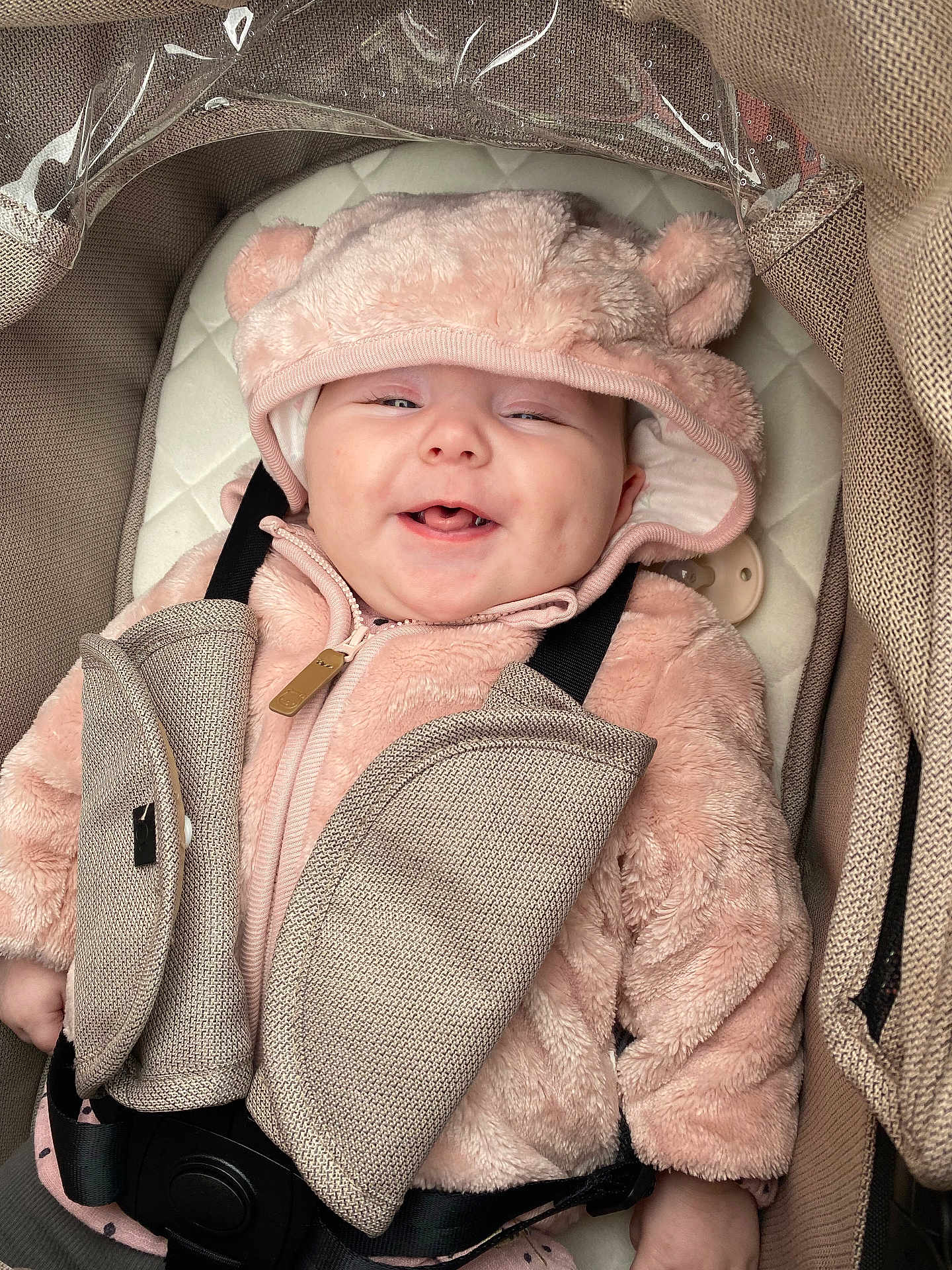 Gracie-Mae is registered to the contest to win money with this photo: baby, smiling, infant, pink_hoodie, car_seat, seatbelt, fluffy_clothing, cute, child, baby_face, happy, indoors, padded, safety, warm_clothing, hood, plush, newborn, transport, comfort
