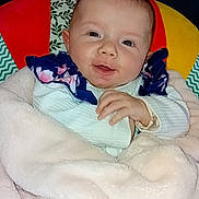 Lya participe au concours pour gagner de l'argent avec cette photo : baby, blanket, child, clothing, colorful, cozy, cushion, cute, face, happy, head, indoor, infant, person, portrait, sitting, smile, soft, wrapped, young