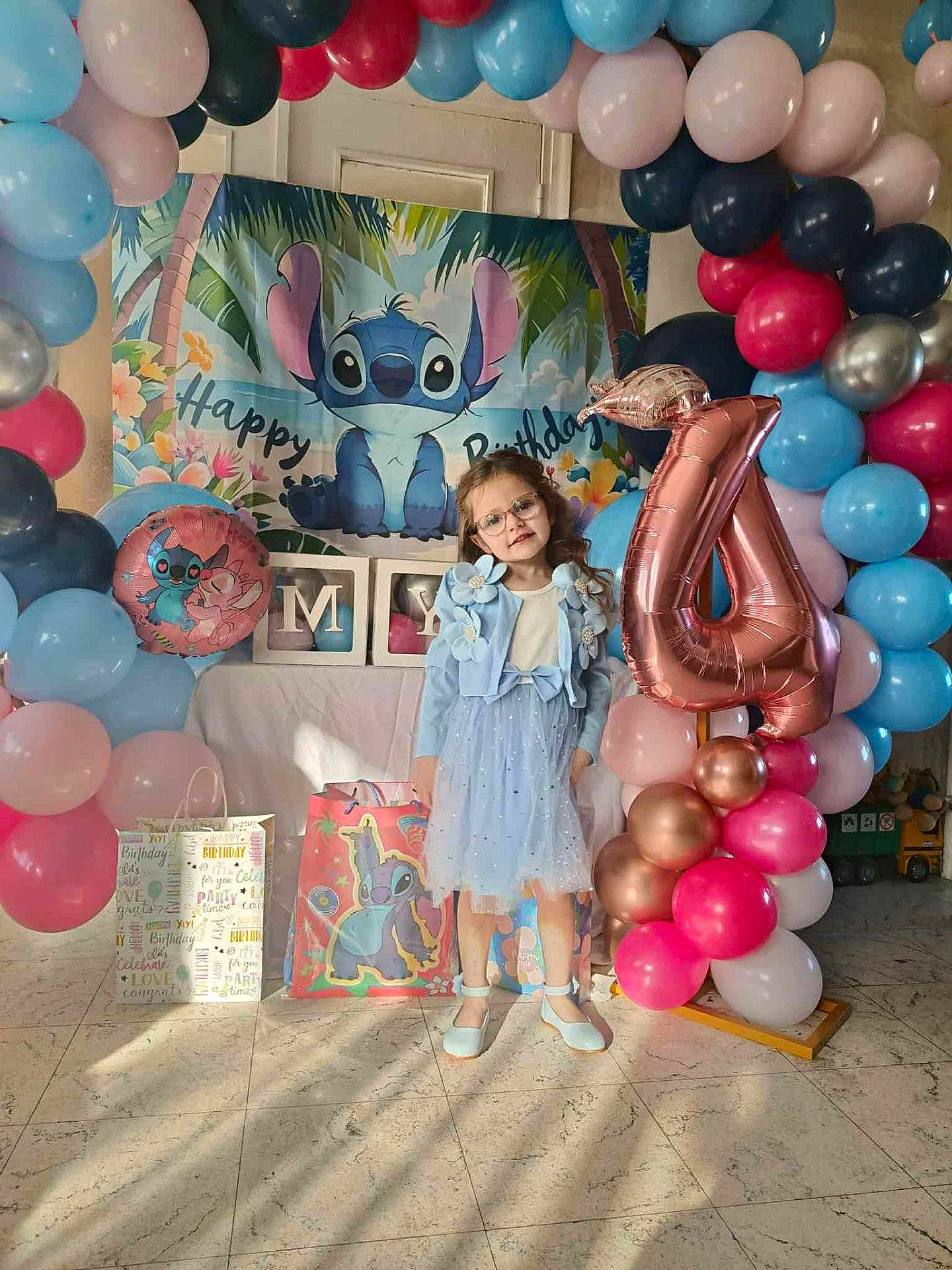 Mya participe au concours pour gagner de l'argent avec cette photo : child, birthday, balloons, blue_dress, glasses, number_4_balloon, gift_bags, floor, marble_floor, party, celebration, stitch_character, pink_balloons, red_balloons, blue_balloons, decorations, smiling, indoor, curly_hair, happy