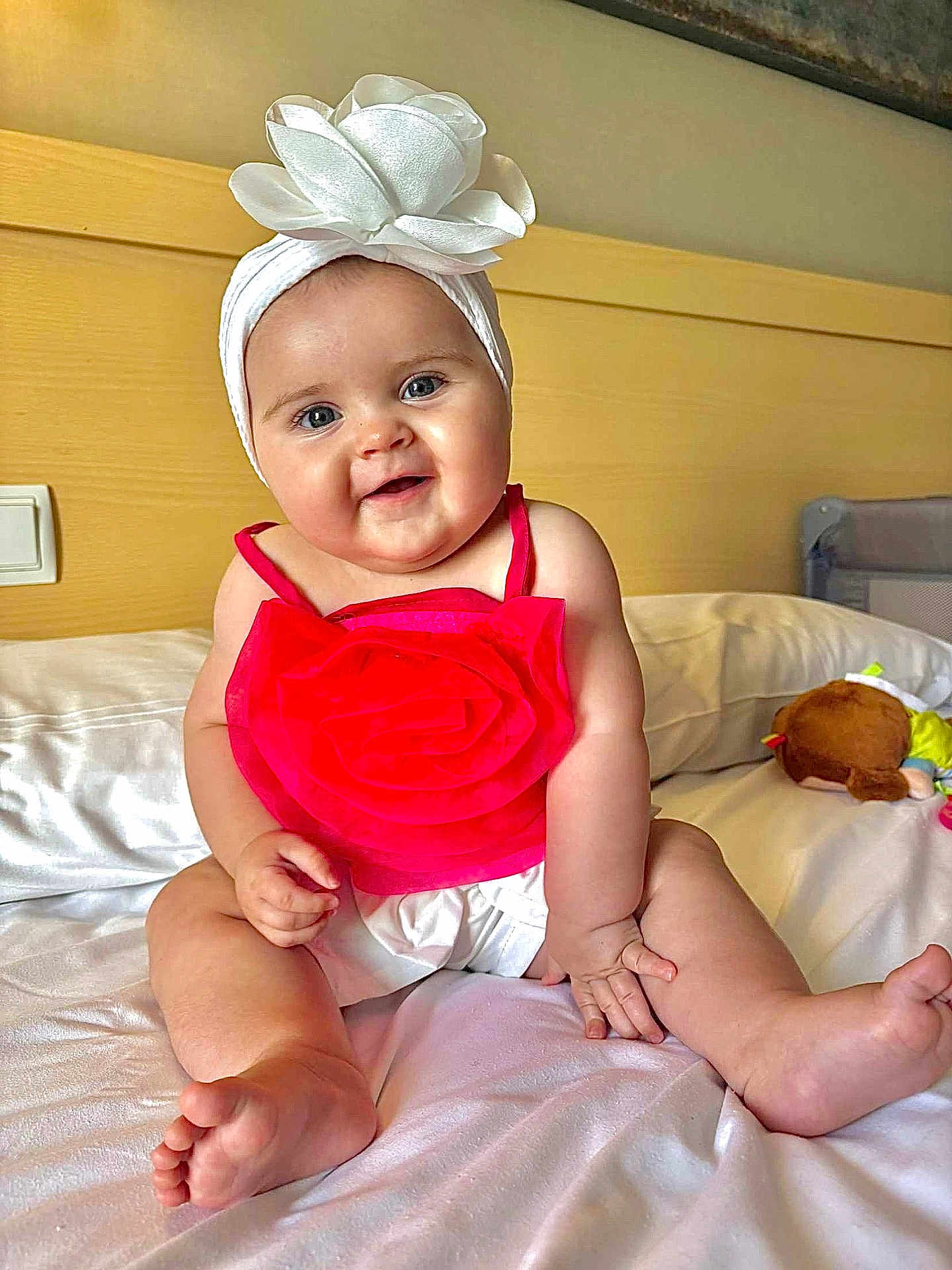 Guiliana participe au concours pour gagner de l'argent avec cette photo : baby, bed, child, cute, flower, foot, hand, happy, headband, indoors, infant, person, pink_top, plush_toy, portrait, sitting, skin, smiling, soft_lighting, white_sheets