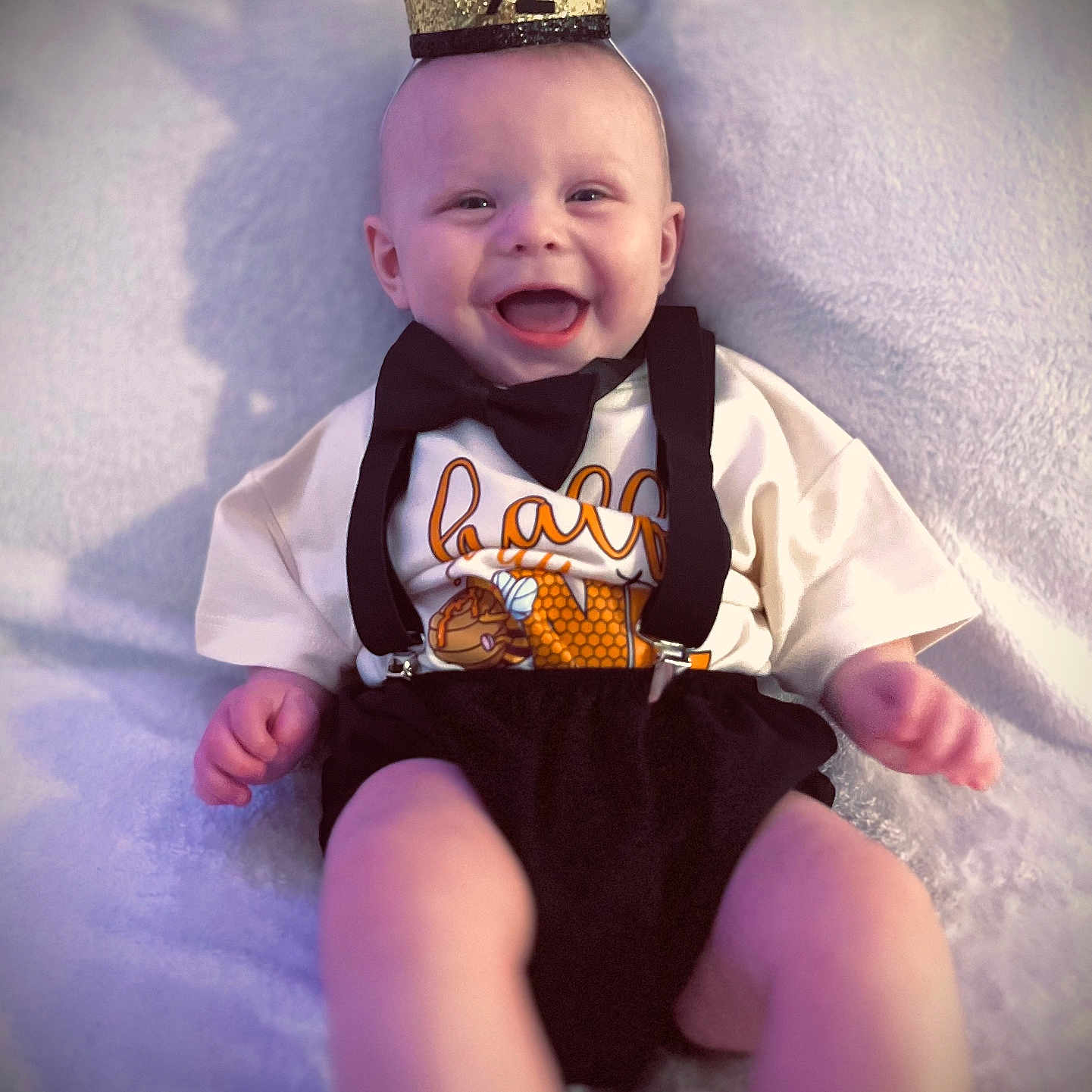 Liam is registered to the contest to win money with this photo: baby, bow_tie, celebration, child, closeup, clothing, crown, cute, face, glitter, half_year, hands, happy, infant, joy, legs, portrait, smiling, soft_blanket, suspenders