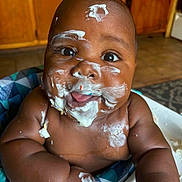 Jayden joined the competition — help win amazing prizes! arm, baby, baby_food, background, cheeks, child, cream, cushion, face, food, happy, high_chair, indoors, messy, mouth_open, pattern, person, skin, smile, wooden_cabinet