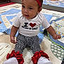baby, child, infant, sitting, headband, red_bow, white_shirt, checkered_pants, ruffles, play_mat, mirror, toys, orange_wall, floor, indoor, cute, smiling, clothing, footwear, person