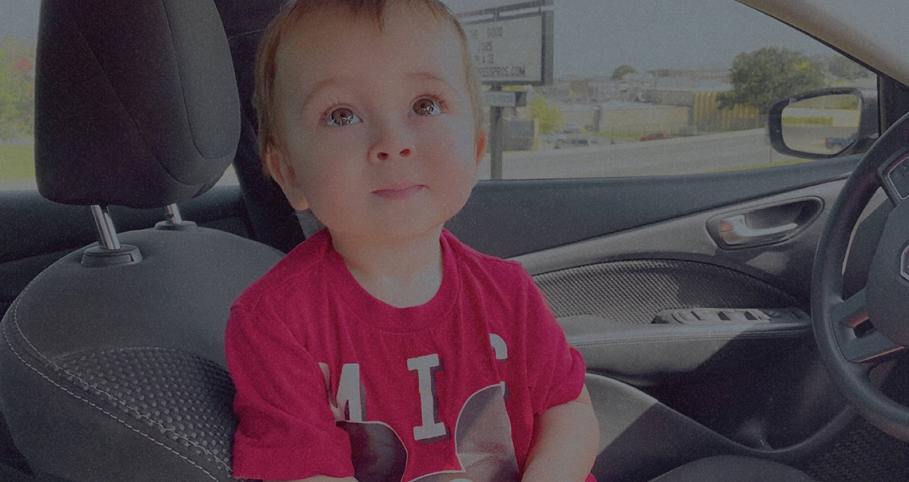 John Michael is registered to the contest to win money with this photo: auto_part, automotive_window_part, car, car_seat, car_seat_cover, child, driving, family_car, head_restraint, person, seat_belt, steering_wheel, toddler, vehicle, vehicle_door