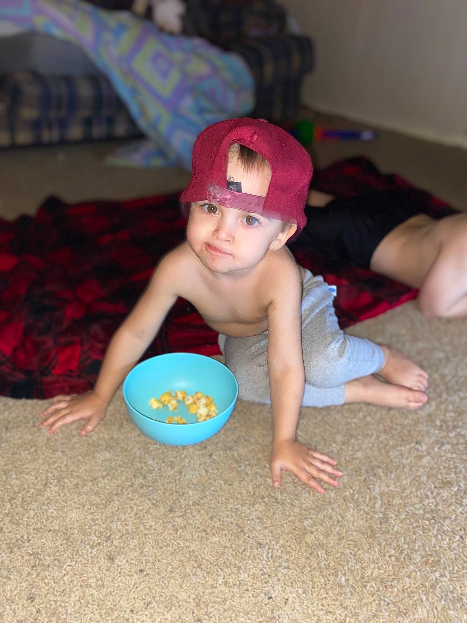 John Michael is registered to the contest to win money with this photo: baby, baby_toddler_clothing, barefoot, cap, child, face, finger, flooring, foot, fun, headwear, human_leg, knee, leisure, person, personal_protective_equipment, room, sitting, t_shirt, thigh