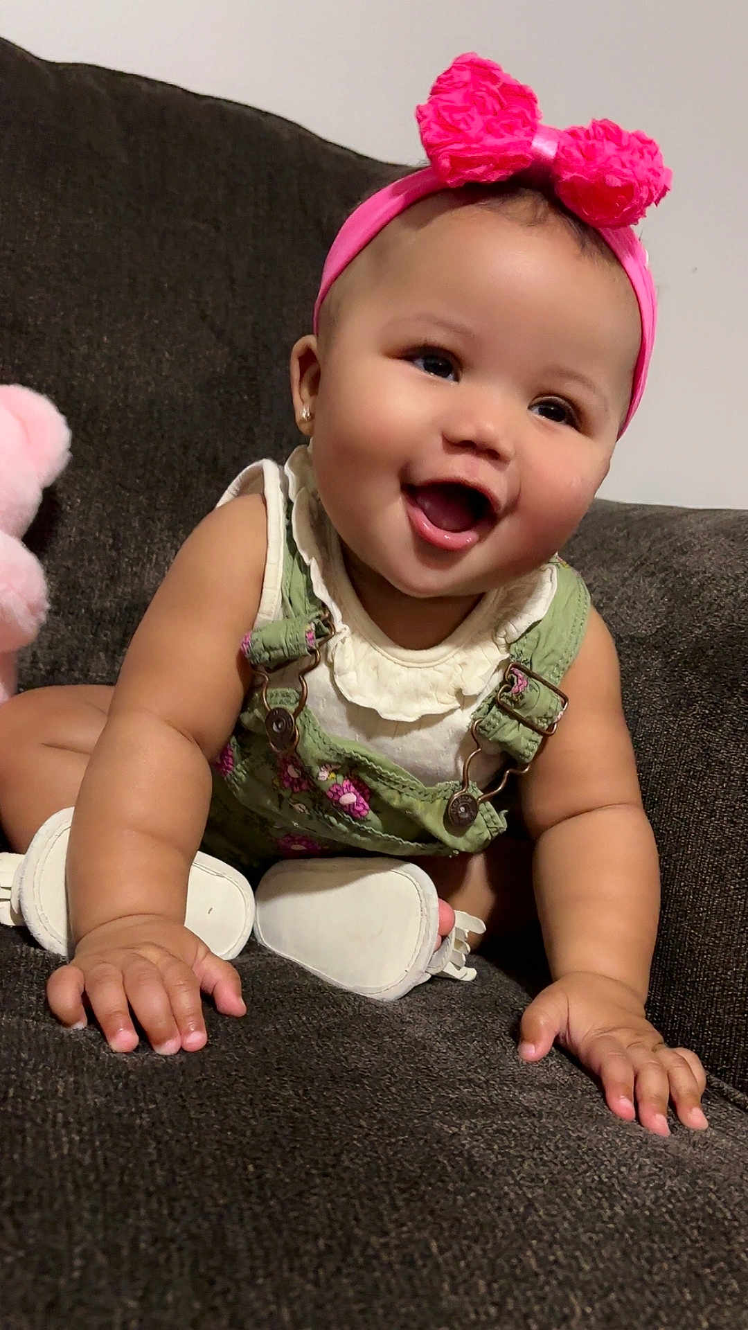 Trinity joined the competition — help win amazing prizes! baby, child, smiling, pink_bow, headband, green_overalls, white_shoes, crawling, happy, cute, indoor, sofa, furniture, infant, portrait, closeup, face, hands, expression, playful