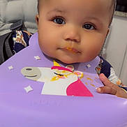 Trinity joined the competition — help win amazing prizes! baby, child, high_chair, bib, unicorn, food, messy, face, eyes, hand, clothing, indoor, cute, infant, portrait, table, feeding, smile, young, adorable