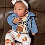 Trinity joined the competition — help win amazing prizes! baby, infant, child, denim_jacket, headband, bow, football_pattern, pants, shirt, sitting, couch, brown_couch, footwear, hand, face, curious, indoors, comfortable, casual_clothing, portrait