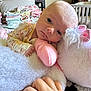 baby, stuffed_animal, unicorn, toy, hand, bedroom, blanket, folded_clothes, nursery, person, infant, soft_toy, cute, child, indoor, sleepy, plush, furniture, pajamas, resting