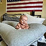 Harlow joined the competition — help win amazing prizes! baby, cushion, bed, flag, american_flag, indoor, smiling, person, infant, clothing, blanket, pillow, head, face, room, wall, decor, cozy, portrait, cute