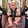 baby, car_seat, child, headband, safety_harness, infant, pink, floral_pattern, cute, seated, indoors, closeup, soft_lighting, straps, footwearless, adorable, expression, small_hands, car_seat_warning, snugride