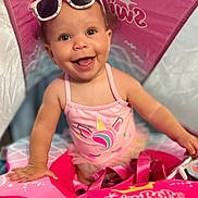 Samarah joined the competition — help win amazing prizes! baby, child, curly_hair, cute, face, float, fun, happy, indoors, person, pink, playful, smiling, summer, sunglasses, swimbobs, swimsuit, toddler, unicorn, water_toy