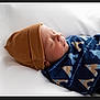 Yésiah is registered to the contest to win money with this photo: newborn, baby, sleeping, hat, blanket, patterned_blanket, cozy, resting, infant, cute, soft, warm, white_background, portrait, side_view, peaceful, child, wrapped, headwear, indoors