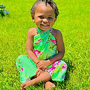 Aurora is registered to the contest to win money with this photo: child, smiling, grass, outdoor, sunny, happy, flower_pattern, barefoot, sitting, green, portrait, cute, nature, person, young, daylight, joyful, colorful, toddler, summer
