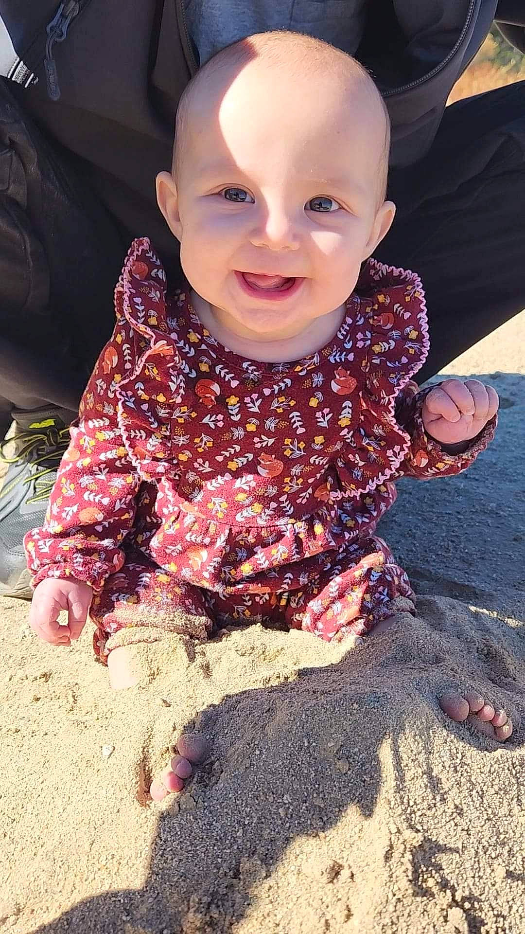 Freya is registered to the contest to win money with this photo: asphalt, baby, baby_toddler_clothing, child, fashion_accessory, flooring, fun, gesture, grass, happy, human_leg, joy, pattern, people_in_nature, person, pink, road_surface, sitting, sleeve, smile