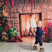 Alessandro participe au concours pour gagner de l'argent avec cette photo : child, toddler, baby, fireplace, presents, gifts, christmas_tree, stockings, decorations, stone_wall, tiles, floor, backdrop, holiday, festive, indoor, cozy, shoes, blue_outfit, portrait