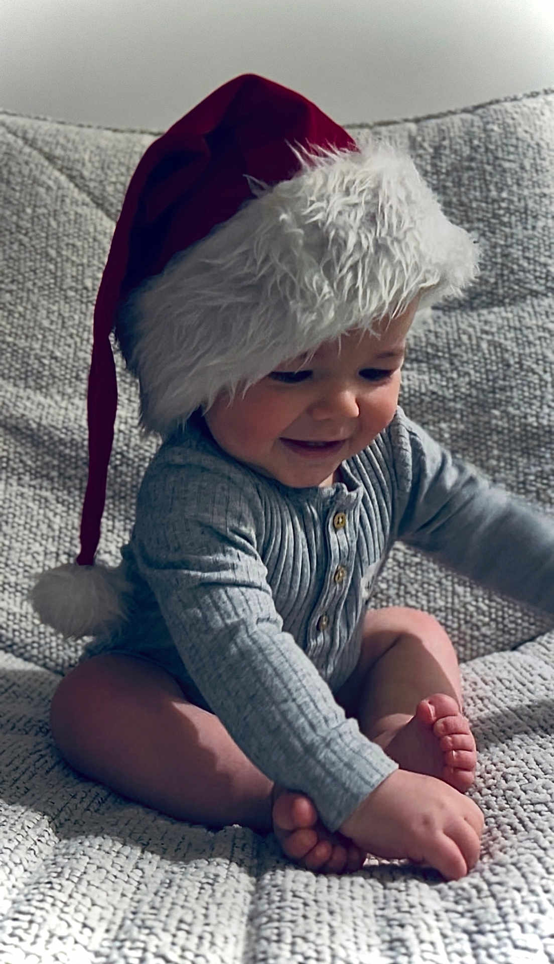 Lenny participe au concours pour gagner de l'argent avec cette photo : baby, child, santa_hat, smiling, cute, indoor, plush, holiday, festive, portrait, happy, infant, cozy, blanket, foot, hand, clothing, cute_expression, sitting, soft_lighting