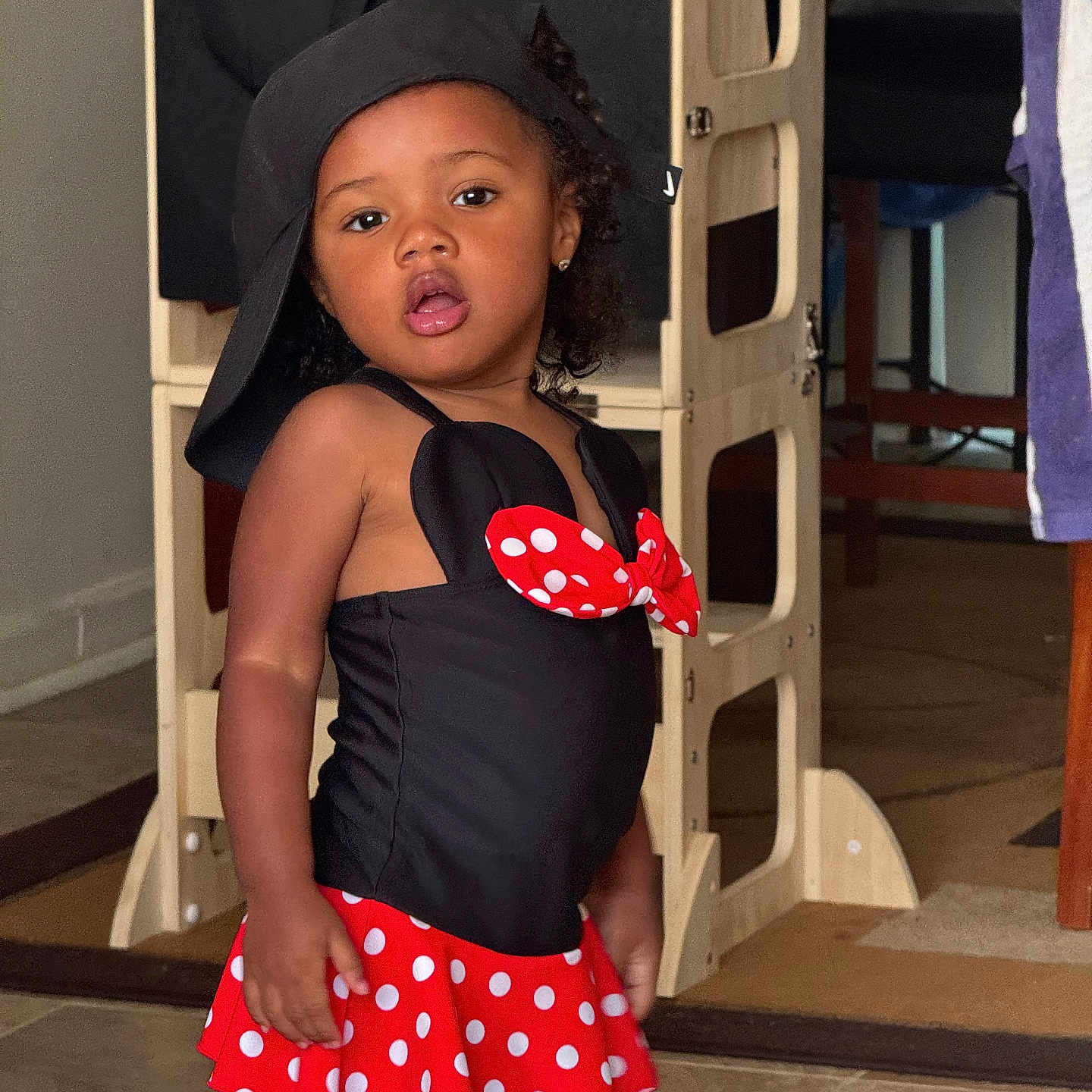 Khonstanz joined the competition — help win amazing prizes! black_top, casual_pose, child, curly_hair, cute, earrings, expression, floor, girl, hat, home, indoor, person, playful_outfit, polka_dot, red_skirt, standing, toddler, wooden_furniture, young