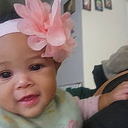 Paulaina is registered to the contest to win money with this photo: baby, child, headband, flower, pink, smile, face, indoors, clothing, person, portrait, cute, young, infant, hand, apparel, wall, decoration, blurred_background, happy