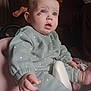 baby, child, infant, polka_dot, seat, blue_eyes, birthmark, clothing, hand, foot, indoor, couch, toy, curious, sitting, person, face, soft_lighting, pink, mint_green