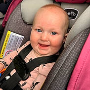 Iris joined the competition — help win amazing prizes! baby, child, car_seat, smile, happy, blue_eyes, safety_harness, pink, gray, clothing, infant, seatbelt, cute, portrait, indoors, person, young_child, sitting, face, expression