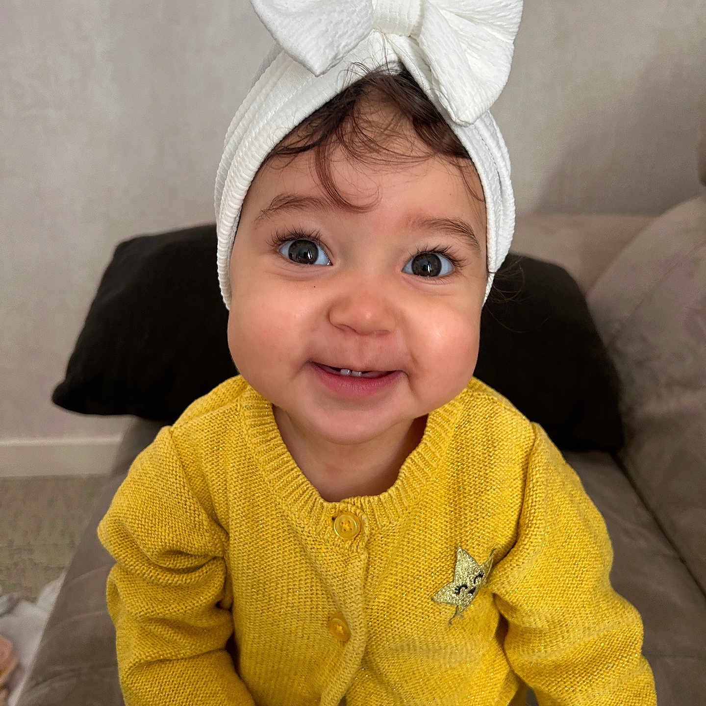 Loëlya a rejoint le concours — aidez-le/la à gagner de superbes lots ! baby, big_eyes, bow_headwrap, cheeks, child, closeup, cushion, cute, face, happy, indoors, knitwear, long_eyelashes, portrait, smile, sofa, teeth, toddler, white_bow, yellow_cardigan