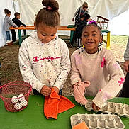 Raelynn joined the competition — help win amazing prizes! activity, basket, braids, child, children, cloth, egg_carton, eggs, girl, group, hair_bun, happy, hoodie, indoor, people, playful, smiling, sweater, table, tent