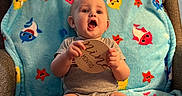 Grayson is registered to the contest to win money with this photo: armchair, baby, bare_feet, blanket, chair, child, colorful, fish_pattern, furniture, gray_outfit, home, indoors, infant, looking_at_camera, milestone, open_mouth, portrait, sitting, smiling, wooden_sign