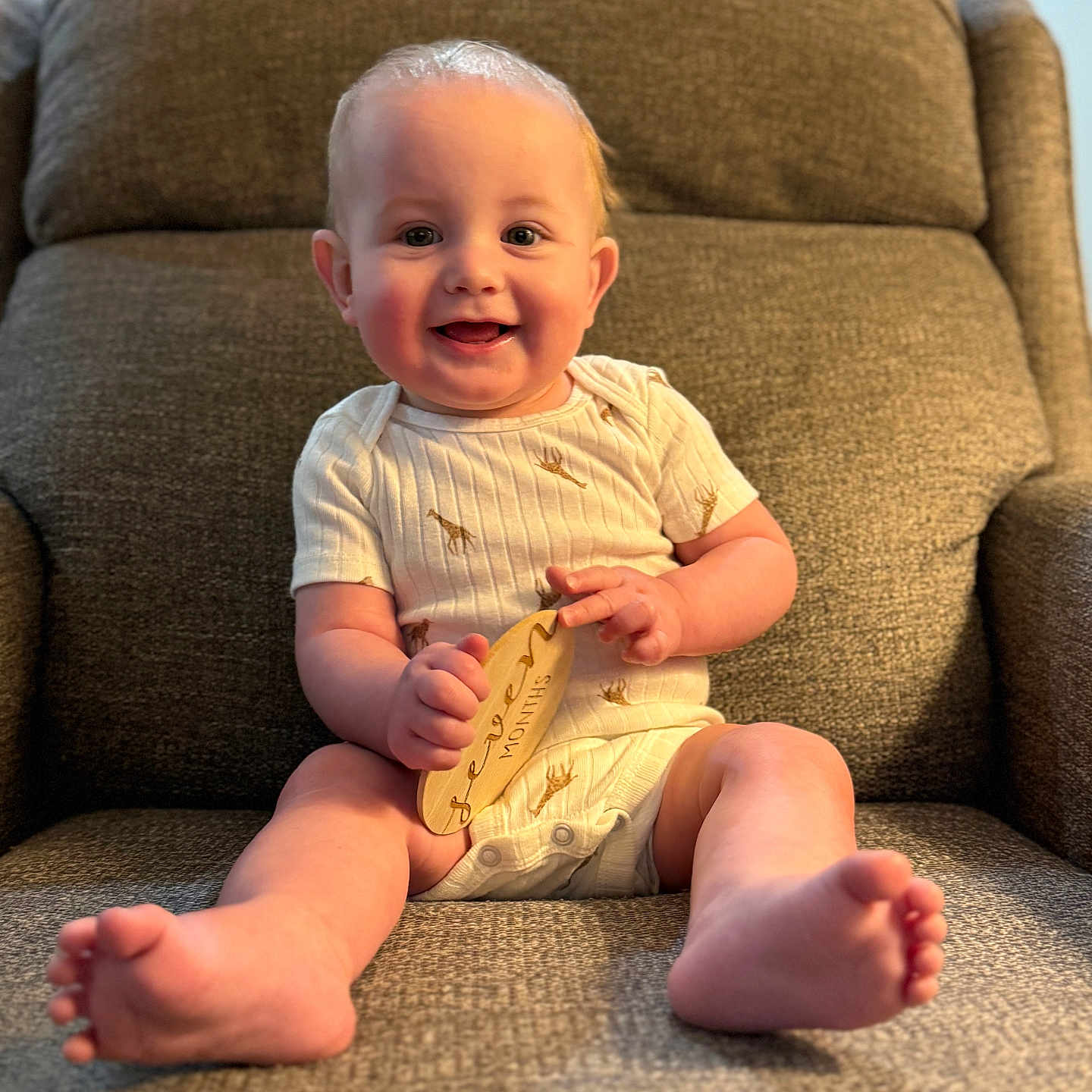 Grayson joined the competition — help win amazing prizes! baby, child, infant, smiling, happy, portrait, sitting, armchair, indoor, home, furniture, clothing, onesie, barefoot, feet, toy, tag, warm_lighting, close_up, family_photo