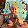armchair, baby, barefoot, blanket, cardinals_shirt, child, colorful, cozy, fish_pattern, furniture, happy, indoors, infant, living_room, portrait, seated, sitting, smiling, sports_shirt, wooden_object