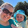 adult, baby, child, selfie, smiling, outdoor, pool, sunny, summer, sun_hat, turquoise_clothing, sunglasses, mother, infant, portrait, family, trees, blue_sky, water, playground