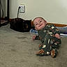 baby, infant, child, smiling, sitting, onesie, animal_print, cat, tortoiseshell_cat, pet, carpet, indoor, home, living_room, wall, electrical_outlet, books, floor, portrait, adorable