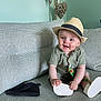 Ollie is registered to the contest to win money with this photo: baby, hat, fedora, green_outfit, couch, gray_couch, beanie, white_object, smile, happy, child, indoor, decor, heart_decor, seated, cute, portrait, person, fashion, playful