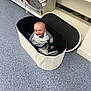 baby, child, storage_basket, floor, shelf, box, indoor, smiling, clothing, footwear, toy, shopping, aisle, home_goods, container, happy, infant, store, product, retail