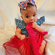 Luna is registered to the contest to win money with this photo: baby, child, infant, dress, headband, fabric, red, blue, stars, flag_pattern, cute, sitting, blanket, soft, indoors, portrait, hand, face, eyes, curious