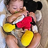 baby, infant, sleeping, pacifier, stuffed_toy, mickey_mouse, plush, baby_seat, cushion, blanket, curly_hair, barefoot, indoor, child, cute, relaxed, soft_lighting, comfortable, resting, toy