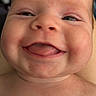 baby, close_up, smiling, tongue_out, chubby_cheeks, face, skin, head, infant, portrait, happy, cute, child, human, expression, eyes, mouth, indoors, blurred_background, skin_texture
