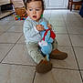 Maël a rejoint le concours — aidez-le/la à gagner de superbes lots ! toddler, child, toy, stuffed_animal, indoor, floor_tiles, blue_eyes, curly_hair, casual_clothing, playtime, building_blocks, natural_light, window, door, home, sitting, brown_shoes, basket, chair, furniture