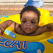 Jevaughn is registered to the contest to win money with this photo: baby, child, pool, float, yellow, water, toddler, swimming, outdoor, sunlight, shadow, towel, steps, skin, curly_hair, relaxation, summer, play, fun, infant