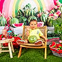 basket, chair, child, colorful, decor, drink, flowers, fruit, grass, greenery, happy, indoor, playful, portrait, smile, summer, table, toddler, watermelon, yellow_clothing