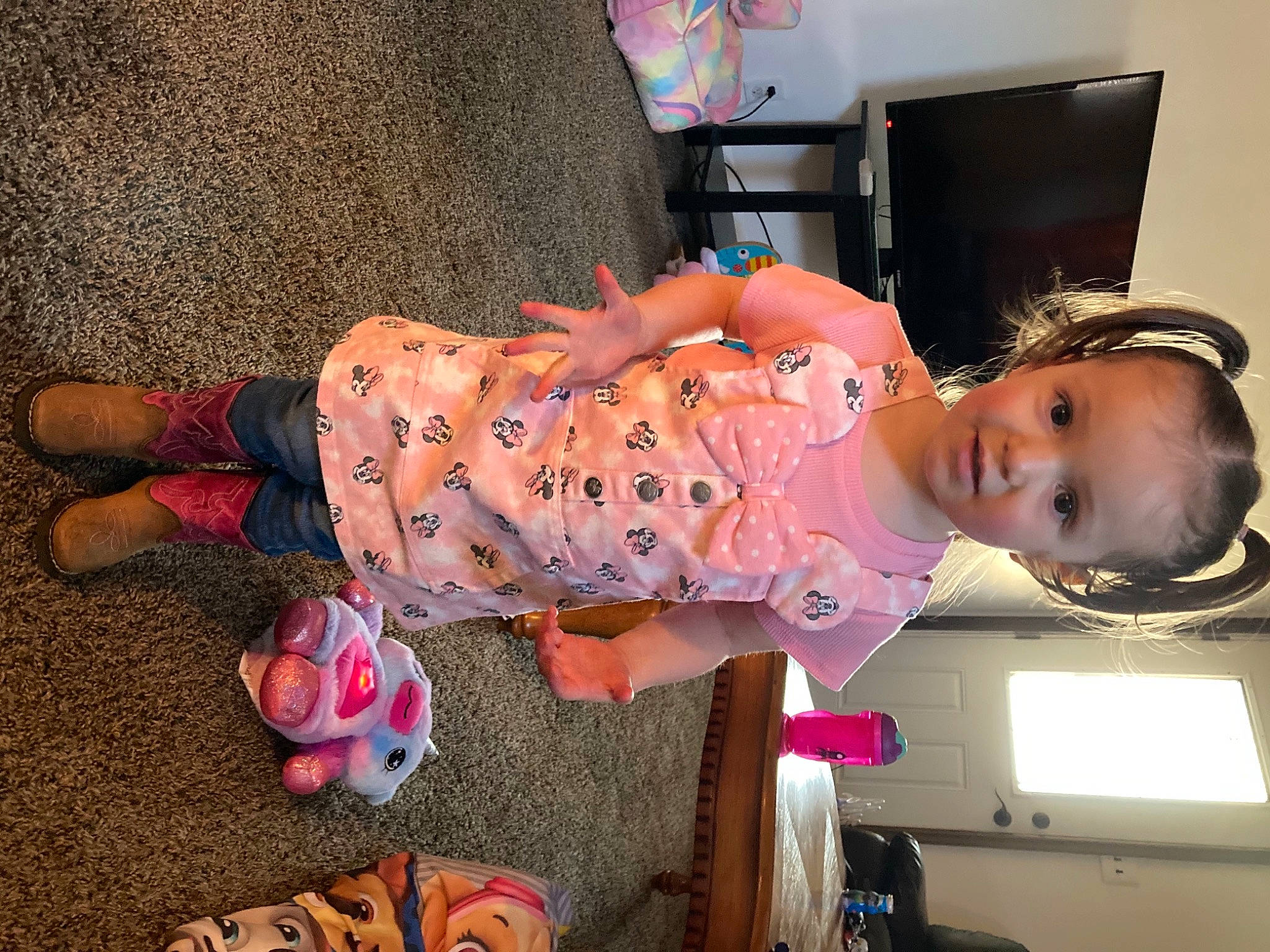 Faye is registered to the contest to win money with this photo: baby, baby_toddler_clothing, child, comfort, costume, flooring, fun, human_leg, nightwear, orange, pattern, person, pink, room, sitting, television, toddler