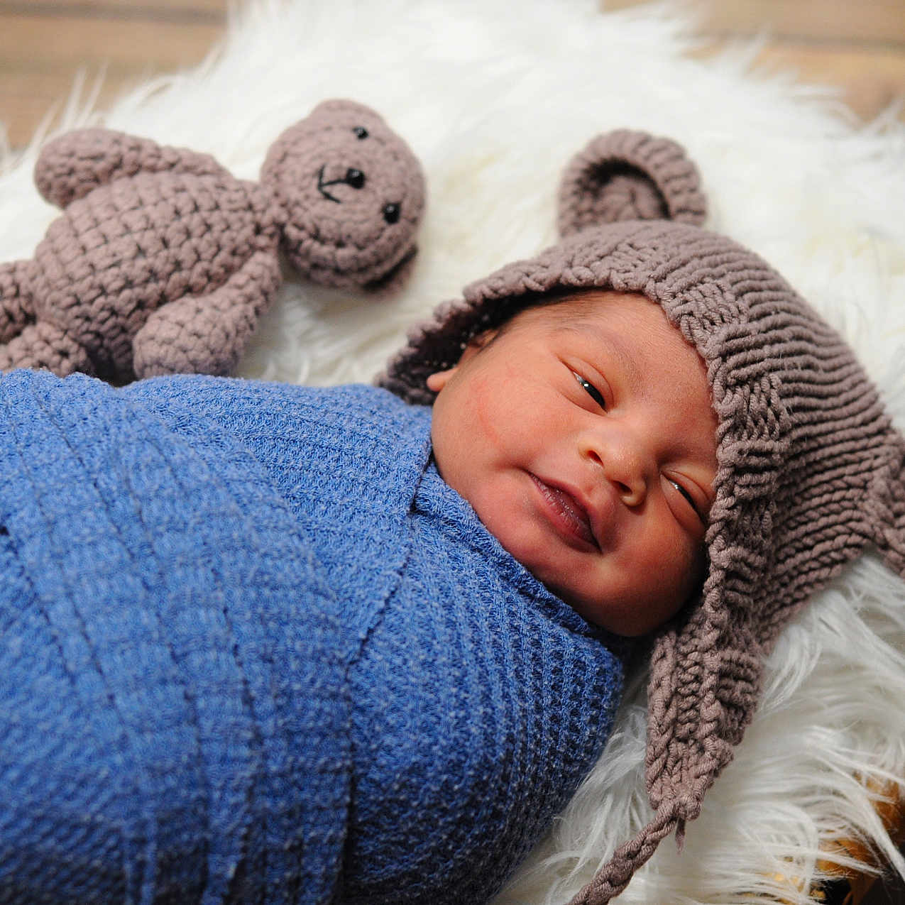 Zseidon is registered to the contest to win money with this photo: baby, bear_ears, blue_blanket, child, cozy, crocheted_toy, cute, fluffy_rug, indoors, infant, knitted_hat, newborn, portrait, resting, sleeping, smiling, soft_texture, teddy_bear, wooden_floor, wrapped
