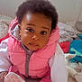 baby, infant, pink_vest, white_sleeves, curly_hair, sitting, blanket, soft_toys, indoor, cute, child, portrait, playful, closeup, floor, clothing, footwear, expression, home, young_child