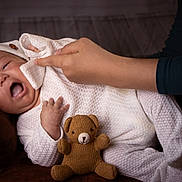 Abisai is registered to the contest to win money with this photo: baby, infant, hand, knitwear, teddy_bear, cushion, white_clothing, cozy, face, expression, child, portrait, indoor, person, cute, newborn, sleepwear, warm, soft, care