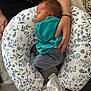 baby, newborn, sleeping, infant, hands, pillow, floral_pattern, clothing, home, blanket, fabric, person, resting, cozy, toddler, soft, comfort, human, cute, portrait