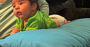 Raiden joined the competition — help win amazing prizes! baby, green_shirt, blue_pillow, couch, infant, person, indoor, child, diaper, curious, soft_lighting, tattoo, seated_adult, black_hair, skin, furniture, relaxed, home, casual, comfort